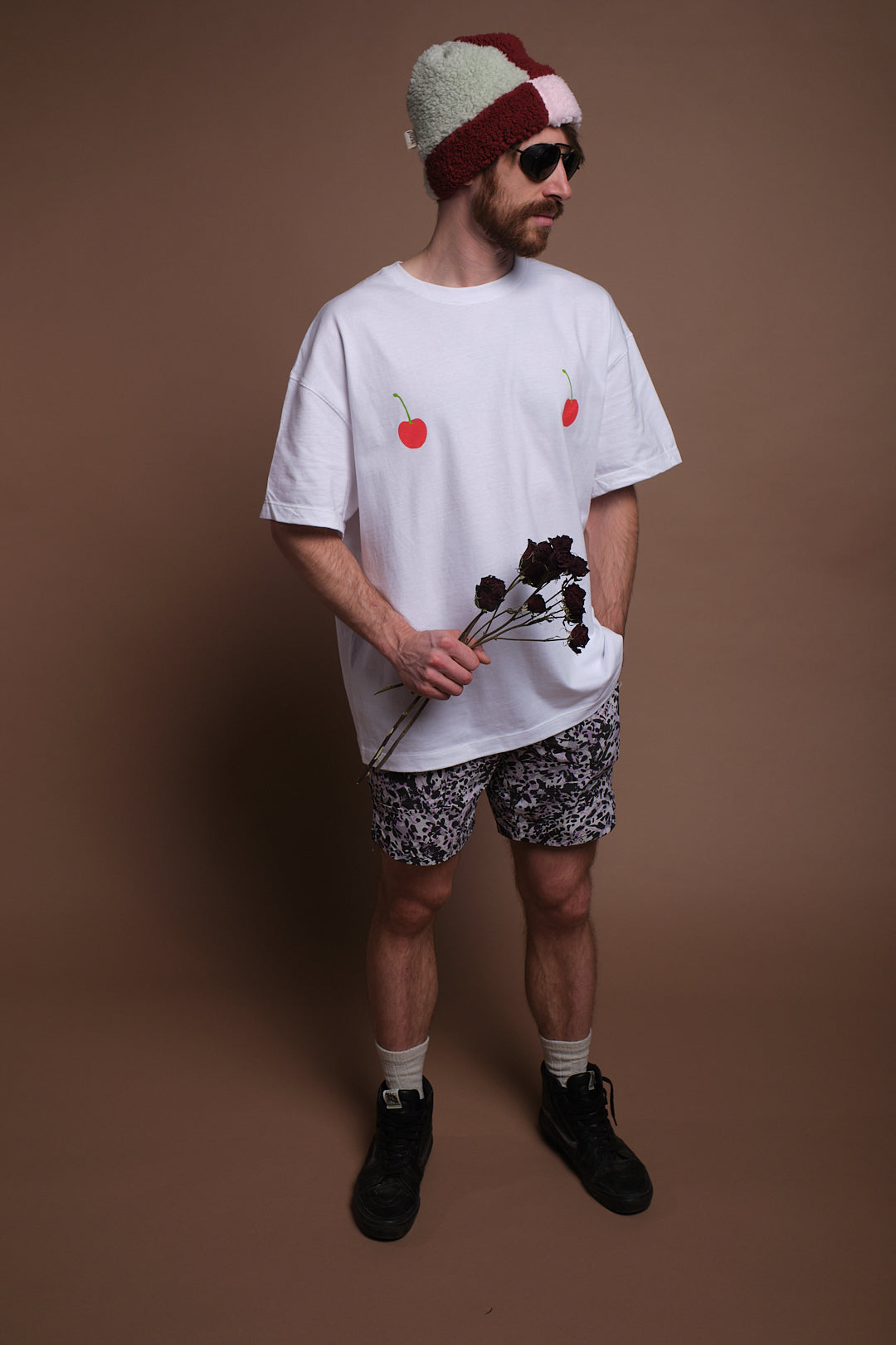 Man holding flowers and wearing  SEND and Renewed Poppy's limited edition t-shirt with SEND's cherry design. 