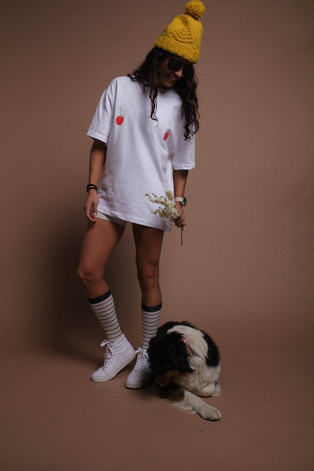 A person standing next to a dog wearing SEND and Renewed Poppy's limited edition t-shirt with SEND's cherry design. 